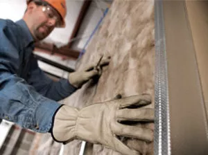Technician installing batt insulation in a wall.