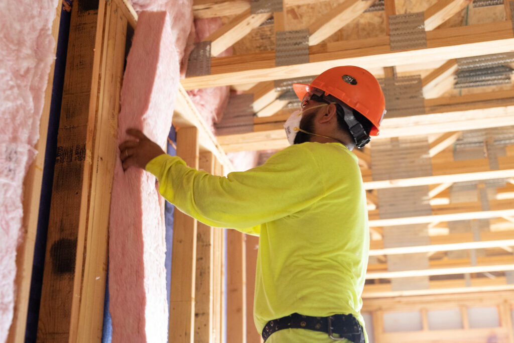 Fiberglass batts being installed into a stud wall